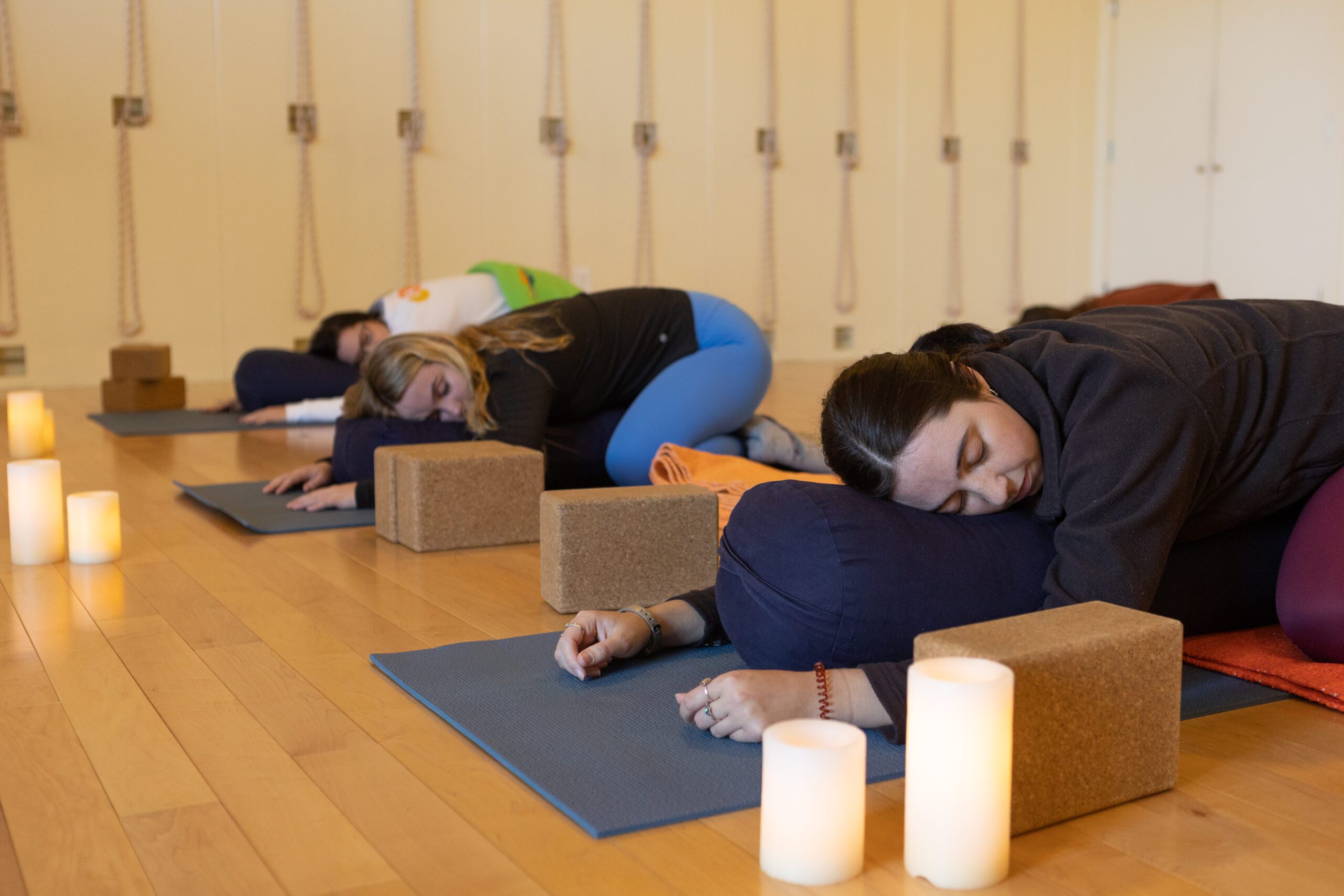 Women in supported child's pose in a restorative yoga class
